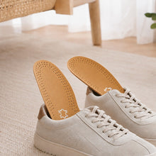 Bruna innersulor i läder med perforering, monterade i ljusa sneakers.