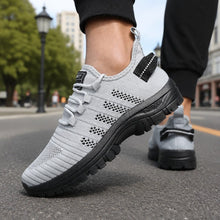 Grå sneakers i mesh med snörning och svart/svartmönstrad yttersula, sidovy.